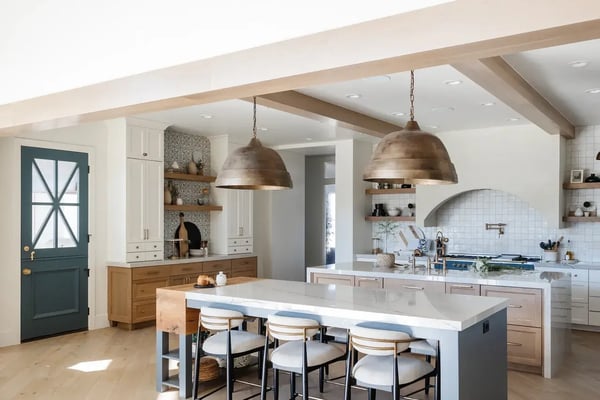Spacious kitchen featuring a mix of wood and white cabinetry, arched range hood, and statement lighting in a Draper, Utah luxury home by E Builders