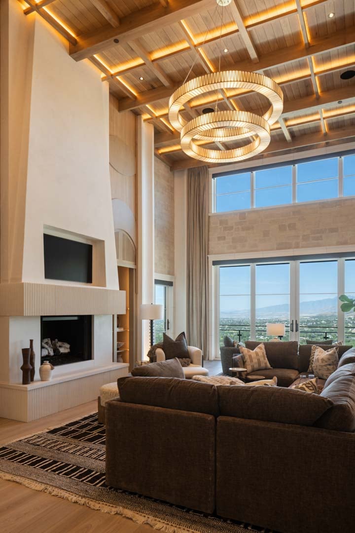 Living room with dramatic fireplace and floor-to-ceiling windows in custom home Room with a View featured in the 2025 Utah Valley Parade of Homes by E Builders Living room with dramatic fireplace and floor-to-ceiling windows in custom home Room with a View featured in the 2025 Utah Valley Parade of Homes by E Builders