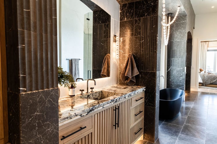 Luxurious master bath with dark stone, floating vanity, and standalone tub in the Room with a View custom home featured in the 2025 Utah Valley Parade of Homes by E Builders