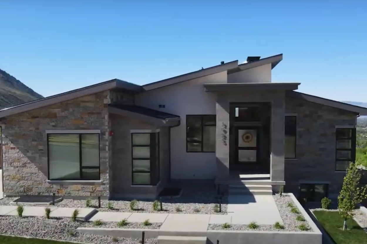 Front exterior view of a contemporary custom home in Utah by E Builders with angled rooflines and stone siding in Alpine (Gallery Page Image)