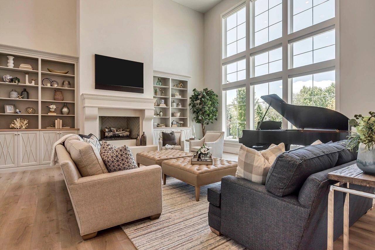 Bright living room with grand piano and fireplace in a custom home by E Builders featured in the 2019 Utah Valley Parade of Homes