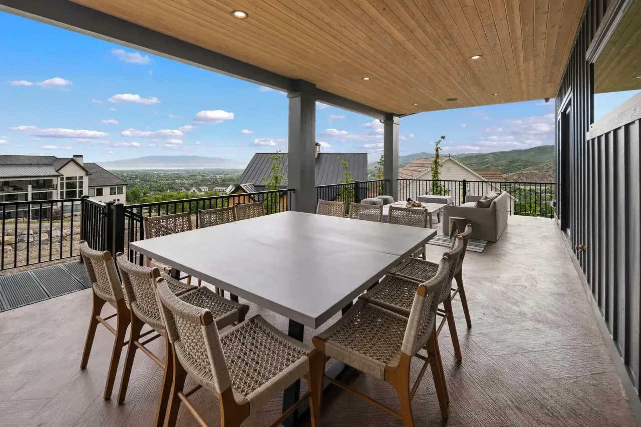 Covered patio with dining and lounge seating in a custom home in Utah Valley by E Builders