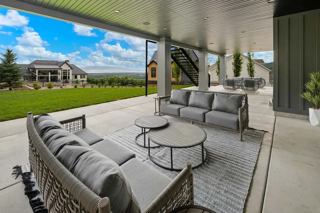 Covered patio with outdoor lounge seating in a custom home in Utah Valley by E Builders