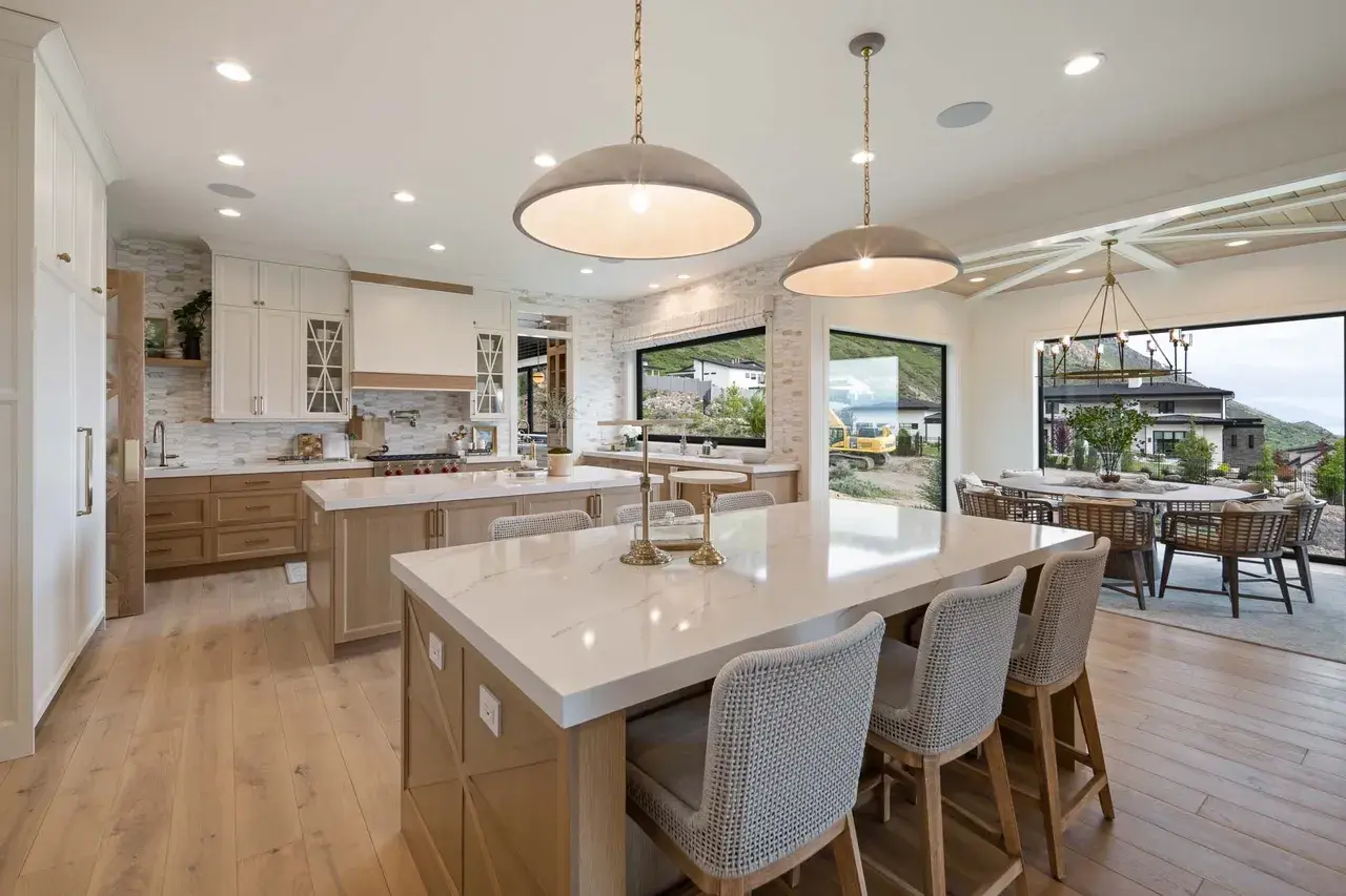 Dual island kitchen with panoramic dining views in a custom home in Utah Valley by E Builders