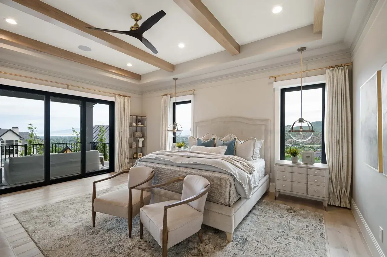 Elegant master bedroom with tray ceiling and balcony in a custom home in Utah Valley by E Builders