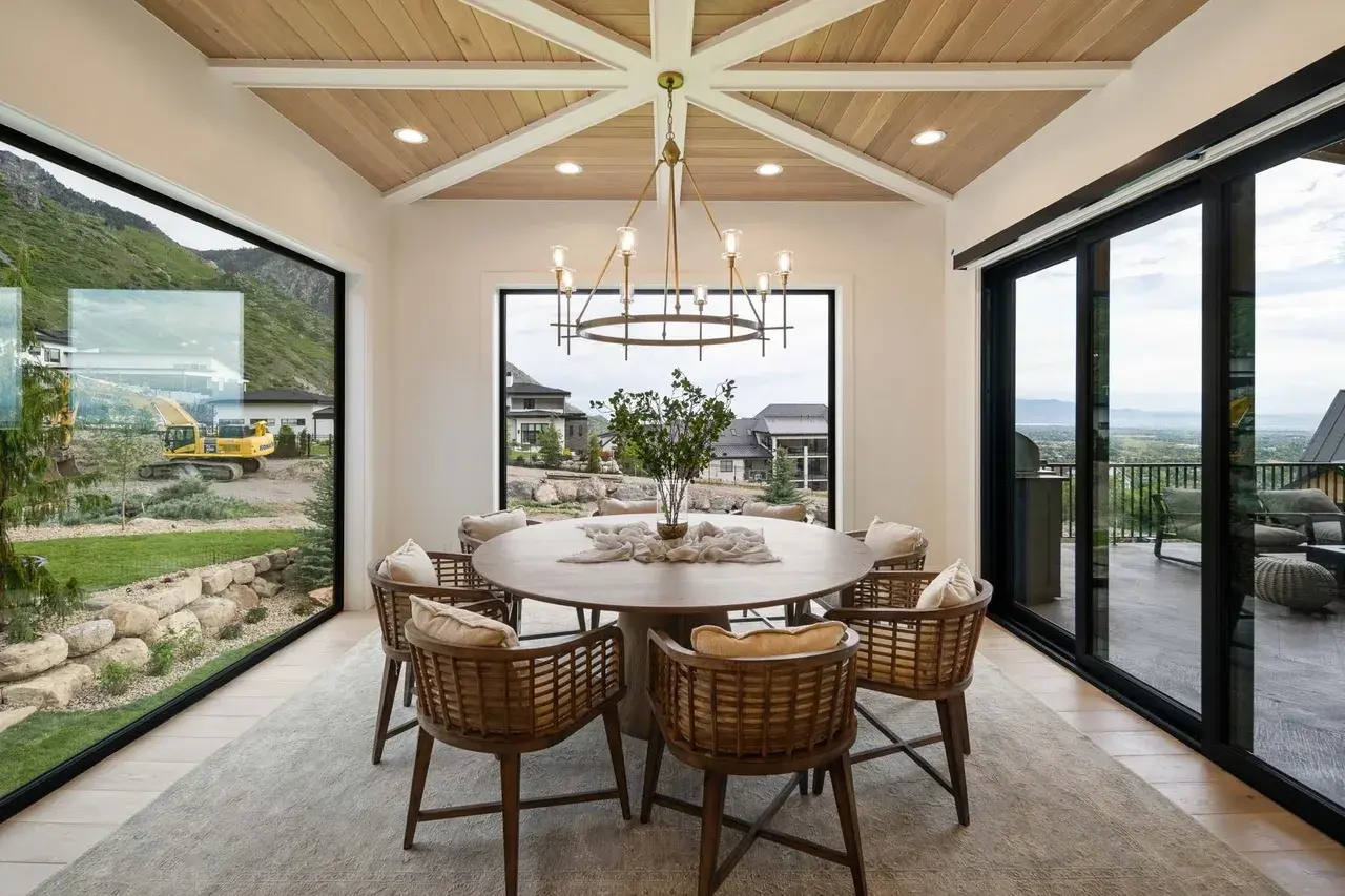Round dining table with chandelier and mountain views in a custom home in Utah Valley by E Builders