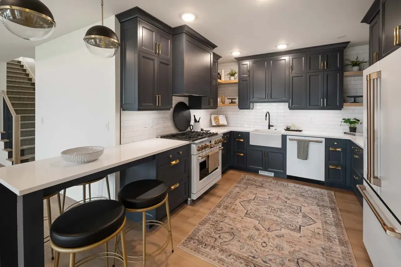 Sleek black and white kitchen with brass accents in a custom home in Utah Valley by E Builders