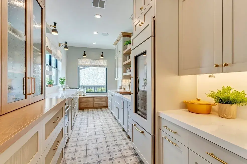 Bright galley-style kitchen with gold accents, white cabinetry, and natural wood elements in a custom home by E Builders, featured in the 2020 Utah Valley Parade of Homes