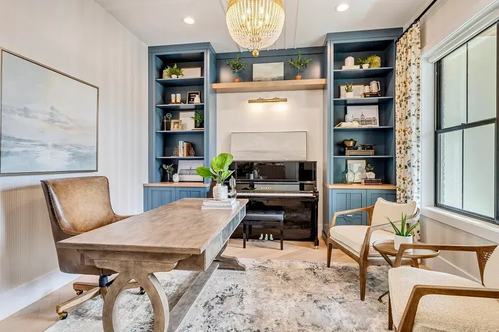 Elegant home office with navy built-in bookshelves, a wooden desk, and a piano in a custom home by E Builders, featured in the 2020 Utah Valley Parade of Homes