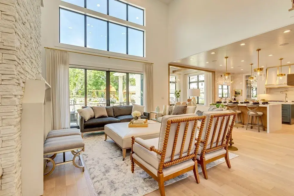 Expansive living room with vaulted ceilings, a stone fireplace, and a wall of windows in a custom home by E Builders, featured in the 2020 Utah Valley Parade of Homes