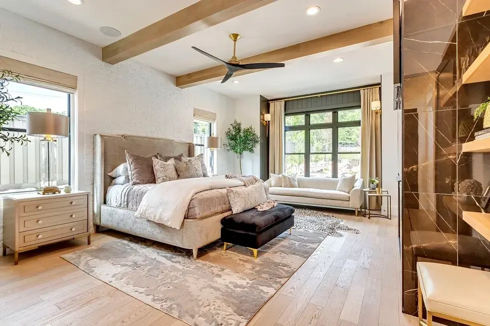 Luxurious master suite with a neutral-toned interior, statement ceiling beams, and a private outdoor view in a custom home by E Builders, highlighted in the 2020 Utah Valley Parade of Homes
