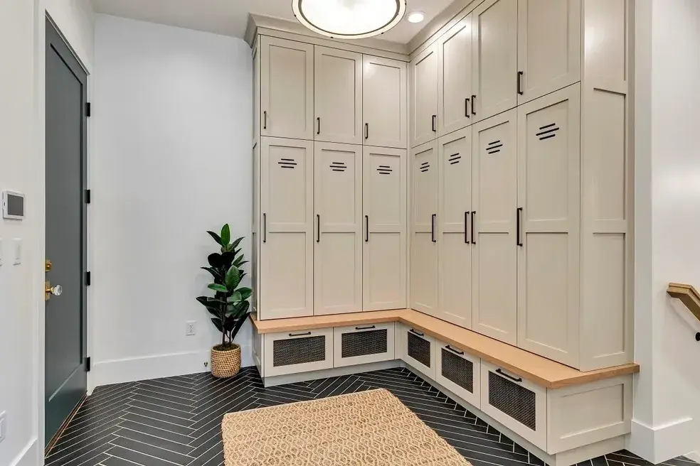Modern mudroom with beige built-in cabinets, black hardware, and a chic wooden bench in a custom home by E Builders, showcased in the 2020 Utah Valley Parade of Homes