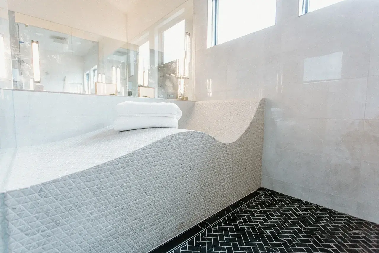 Built-in tiled spa lounger in a luxury shower space of a contemporary custom home in Utah by E Builders