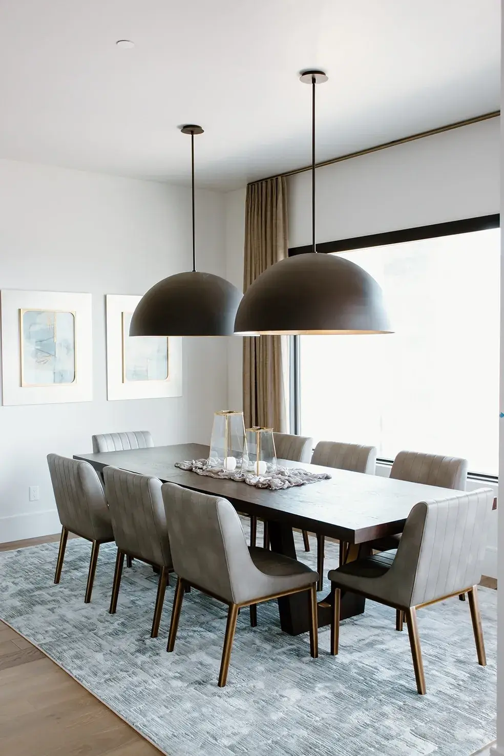 Elegant dining space with a dark wood table and oversized pendant lights in a contemporary custom home in Utah by E Builders