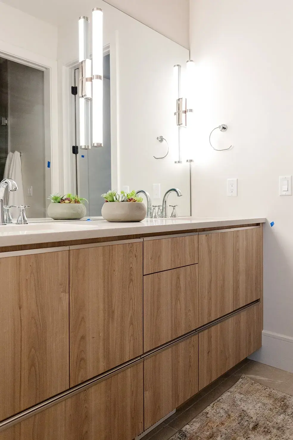 Floating vanity with a sleek wood finish and modern lighting in a contemporary custom home in Utah by E Builders
