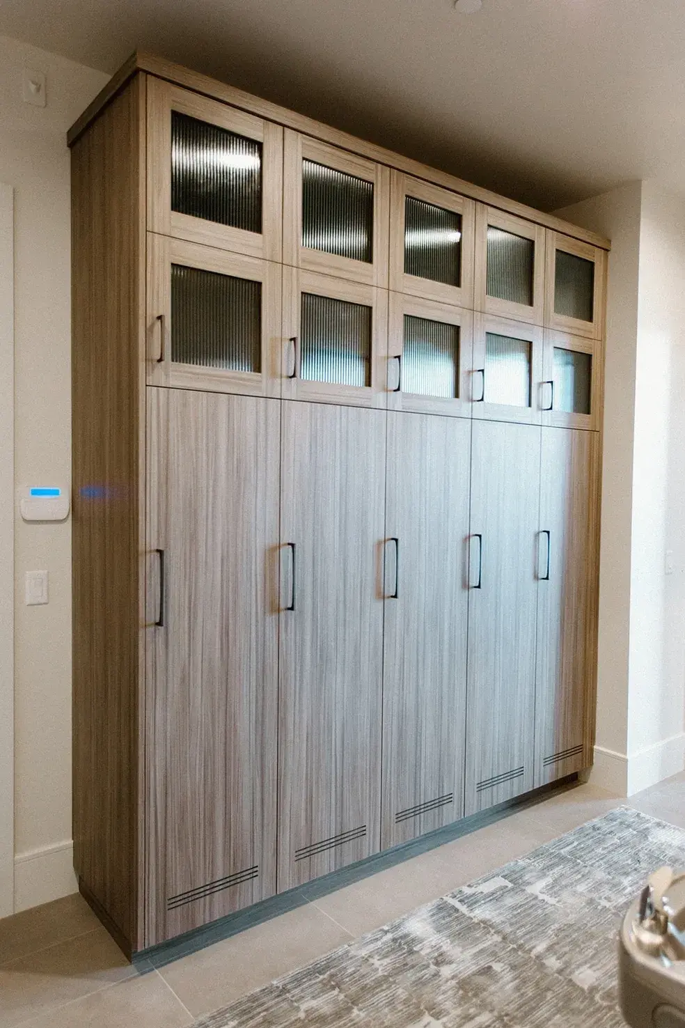 Floor-to-ceiling storage cabinet with glass panels in a contemporary custom home in Utah by E Builders.