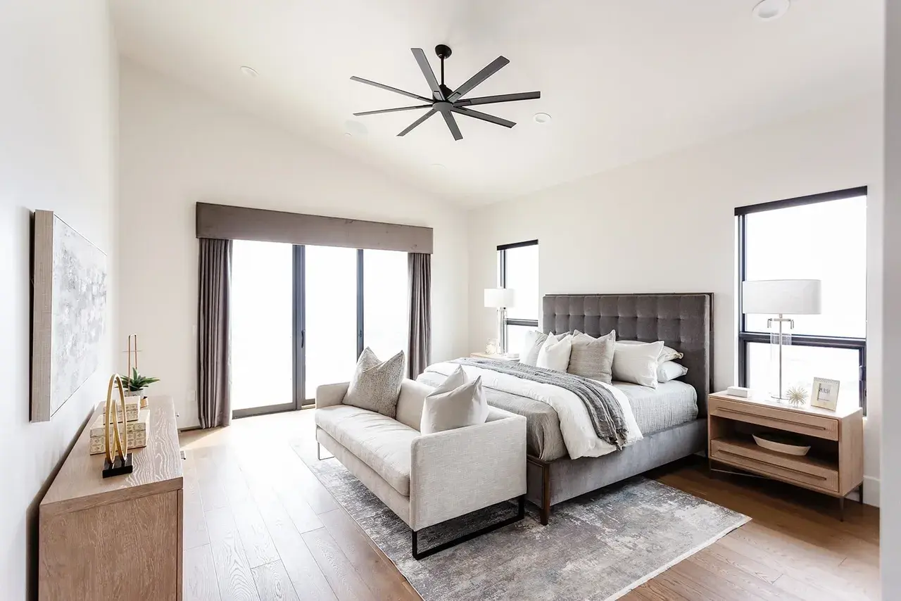 Luxury bedroom featuring a statement ceiling fan and a private balcony in a contemporary custom home in Utah by E Builders