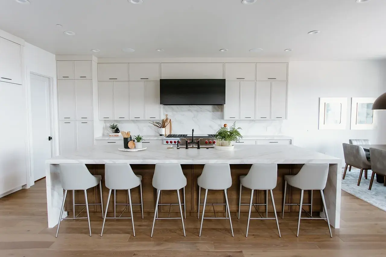 Luxury kitchen with a large waterfall island and sleek bar seating in a contemporary custom home in Utah by E Builders