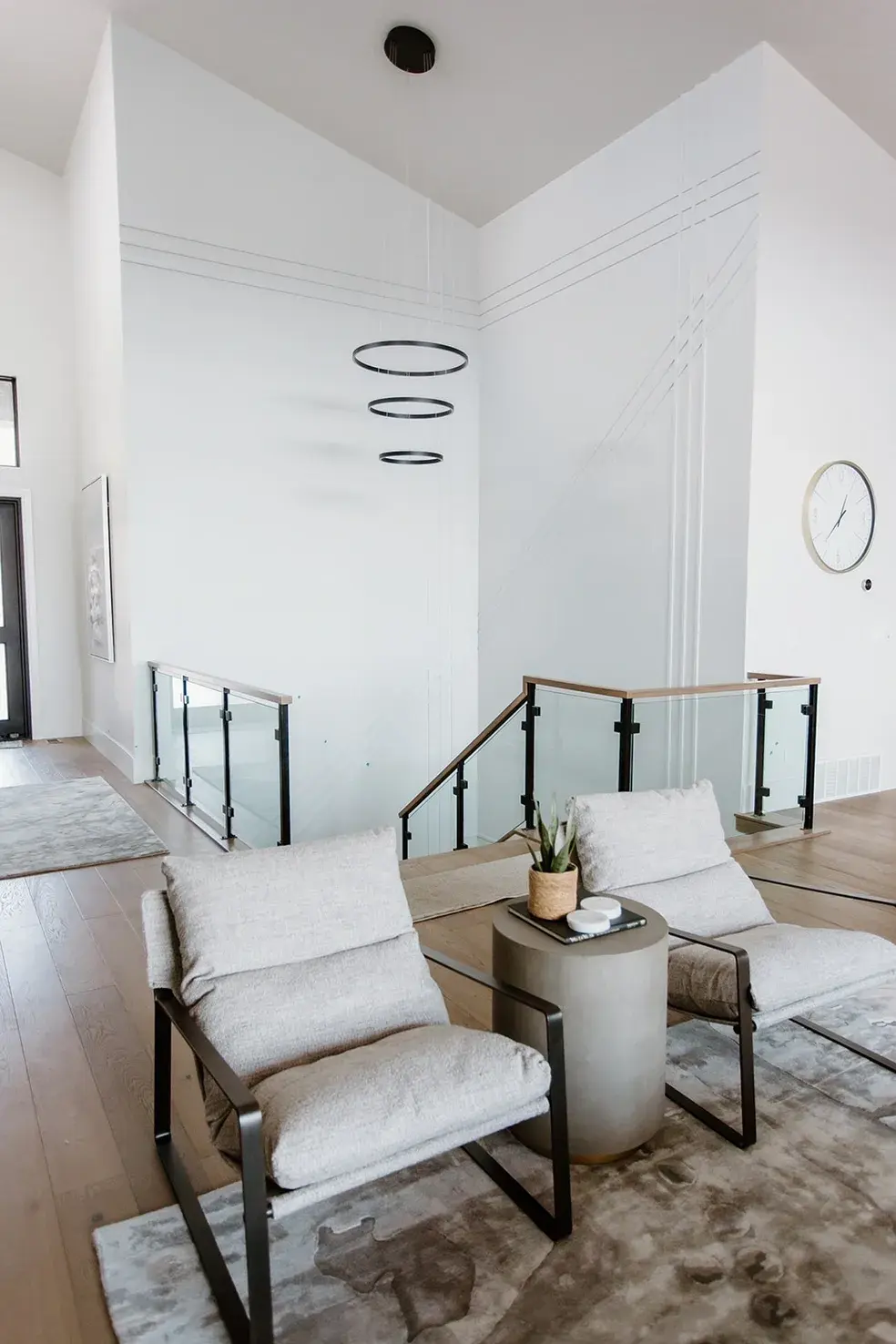 Minimalist seating area with glass railings and modern lighting in a contemporary custom home in Utah by E Builders