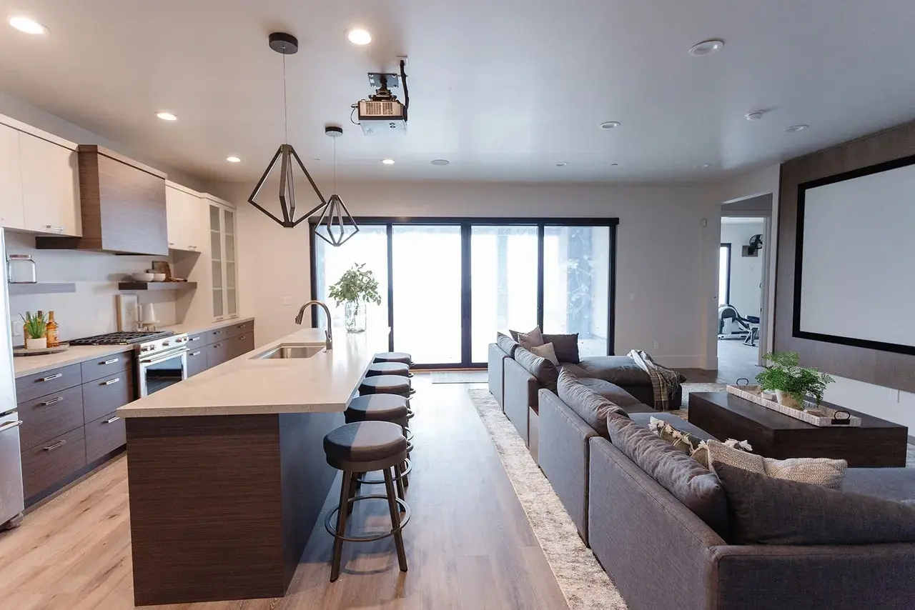 Modern home theater and kitchen space with sleek pendant lighting in a contemporary custom home in Utah by E Builders