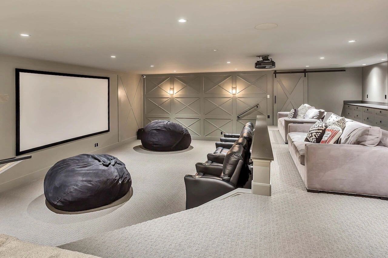 Home theater with tiered seating and large screen in a custom home in Draper, UT by E Builders
