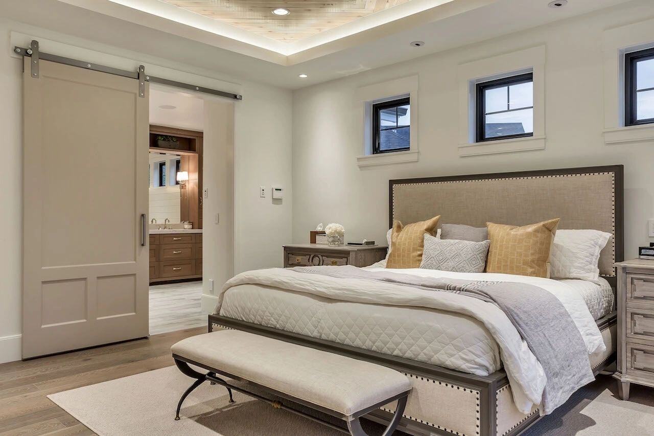 Primary bedroom featuring farm door to bathroom by E Builders in Utah