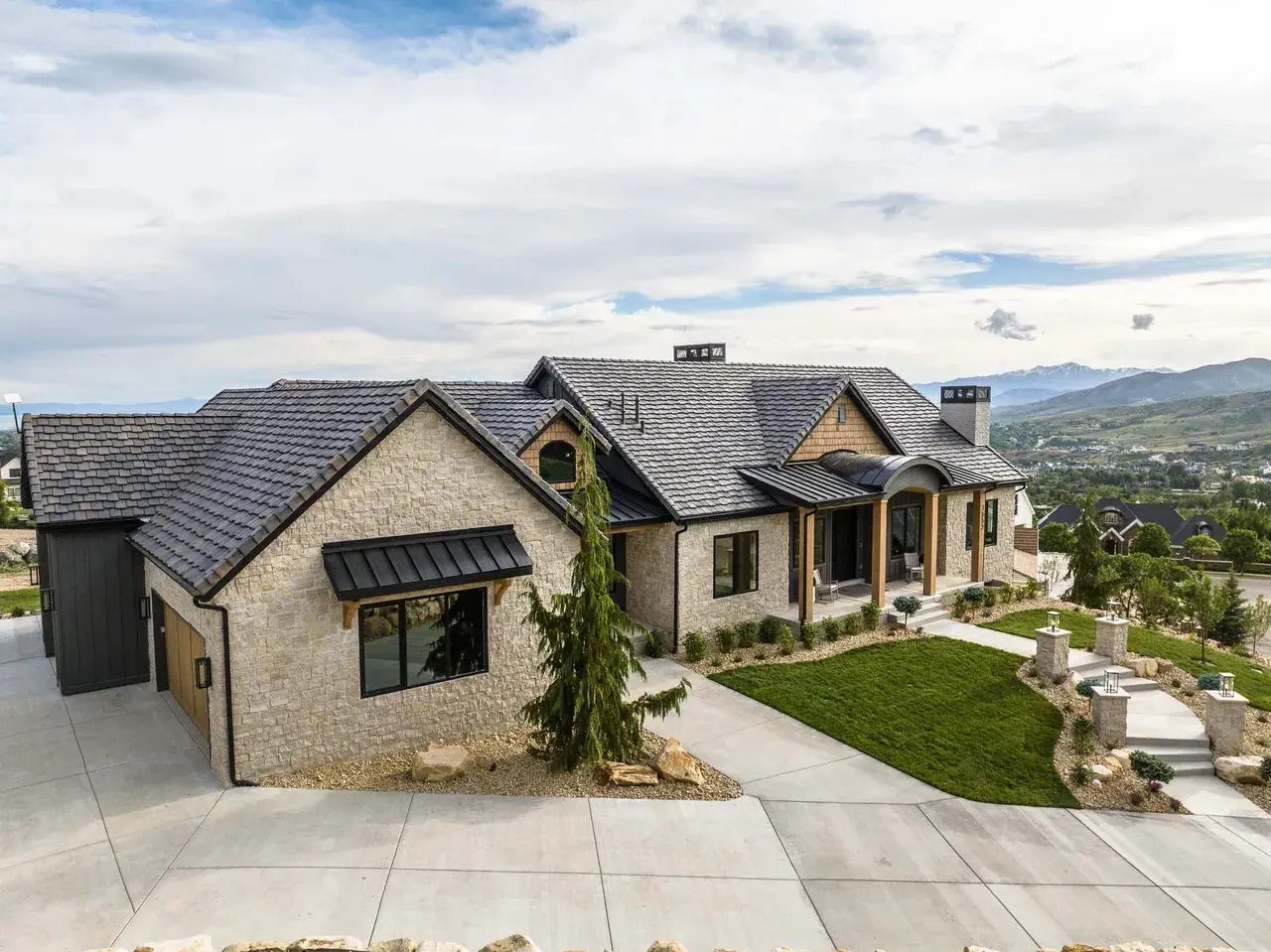 Side front exterior of custom home featuring stone and landscaping in Utah by E Builders