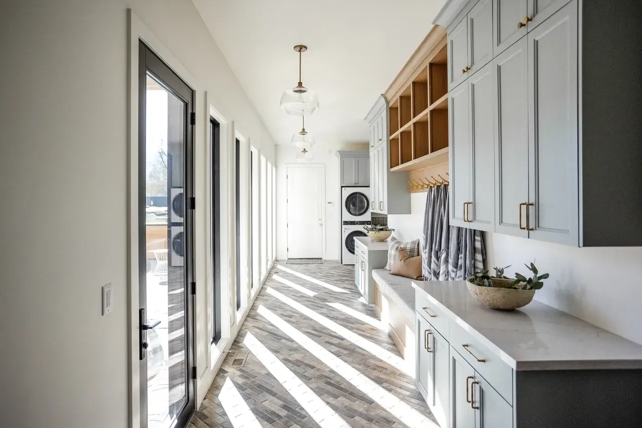 Bright and functional mudroom featuring storage lockers, a laundry area, and modern fixtures in a Draper, Utah luxury home by E Builders