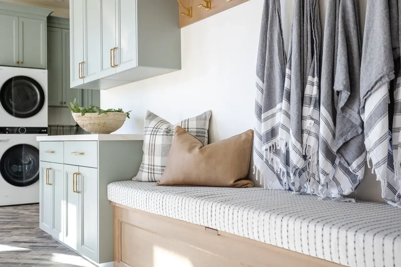Bright and functional mudroom with built-in seating, soft blue cabinetry, and gold hardware in a luxury custom home in Draper, Utah by E Builders