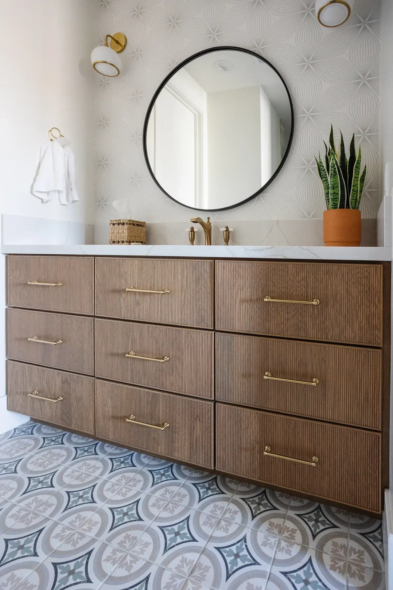 Chic bathroom design with a floating vanity, modern sconces, and geometric tile flooring in a luxury custom home in Draper, Utah by E Builders