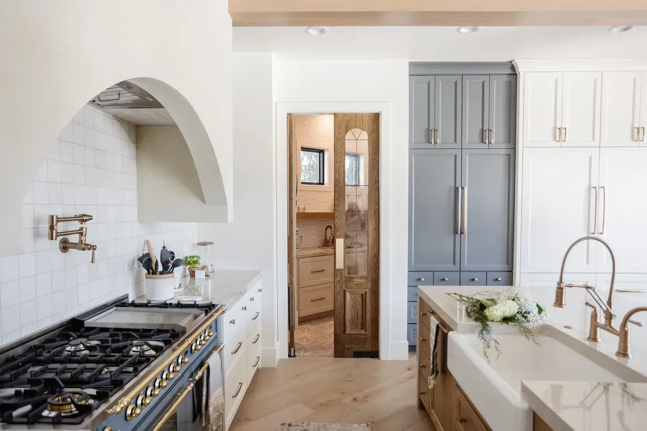Elegant kitchen detail showcasing a European-style gas range, farmhouse sink, and custom cabinetry in a Draper, Utah luxury home by E Builders