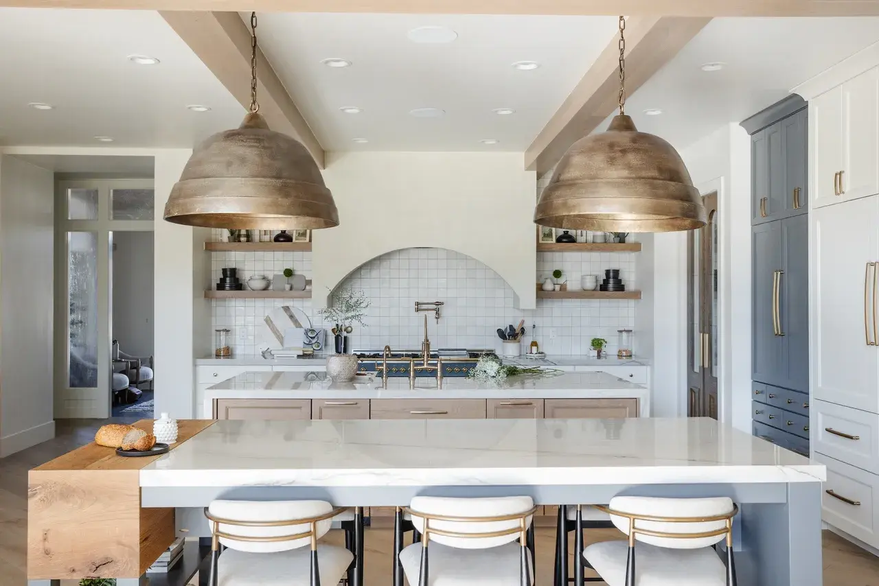 Elegant kitchen featuring a spacious island with white quartz countertops and rustic brass lighting in a Draper, Utah luxury home by E Builder
