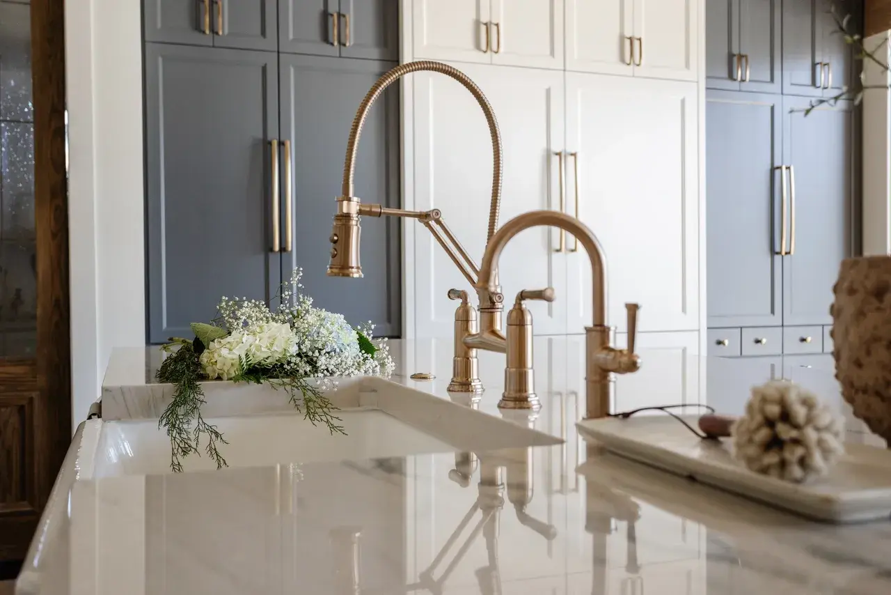 Elegant kitchen sink with a gold faucet and custom cabinetry in a luxury custom home in Draper, Utah by E Builders