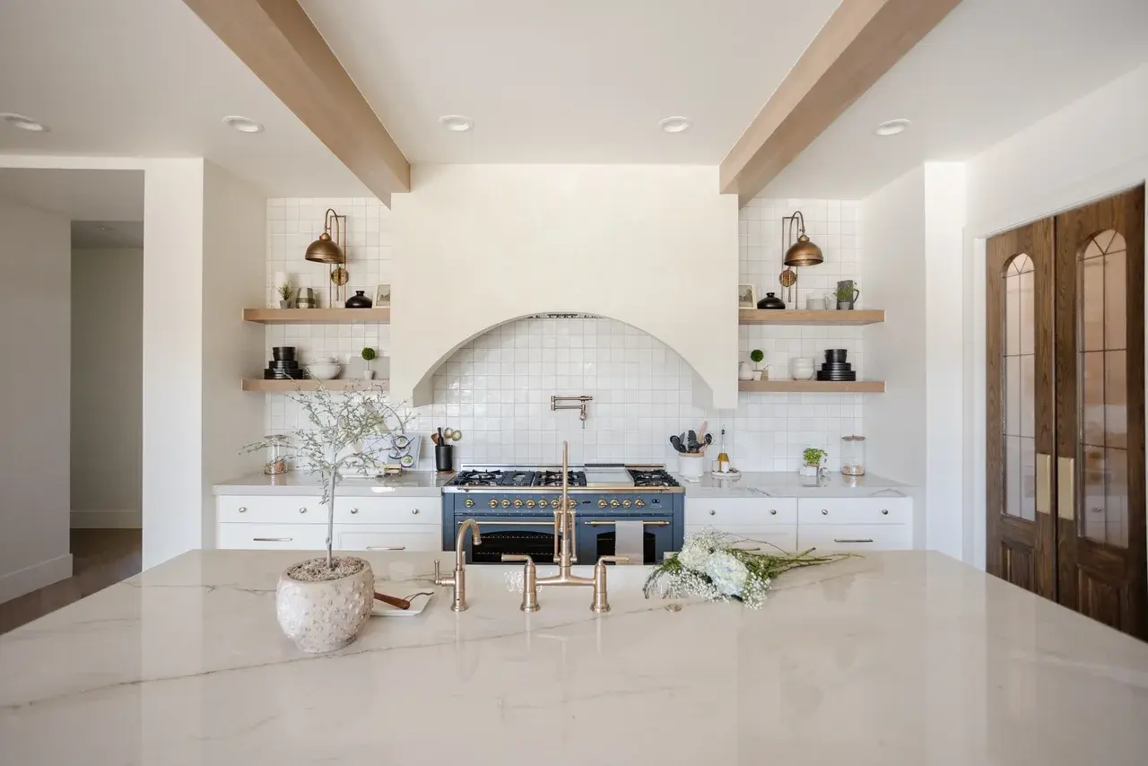 Elegant kitchen with a spacious white island, brass fixtures, and a high-end blue range in a luxury custom home in Draper, Utah by E Builders
