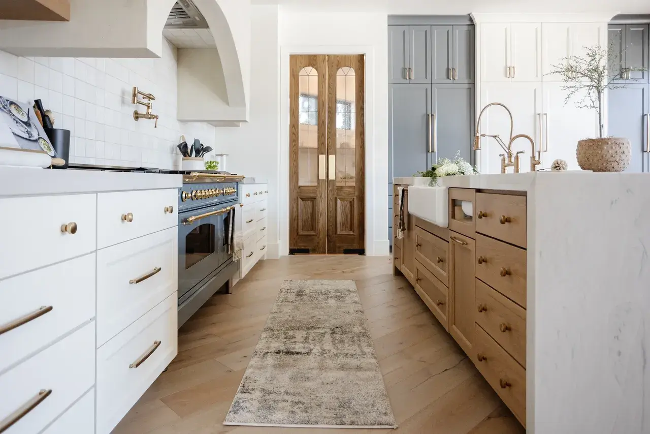 Modern European-style kitchen with mixed cabinetry, a high-end range, and custom double doors in a luxury custom home in Draper, Utah by E Builders