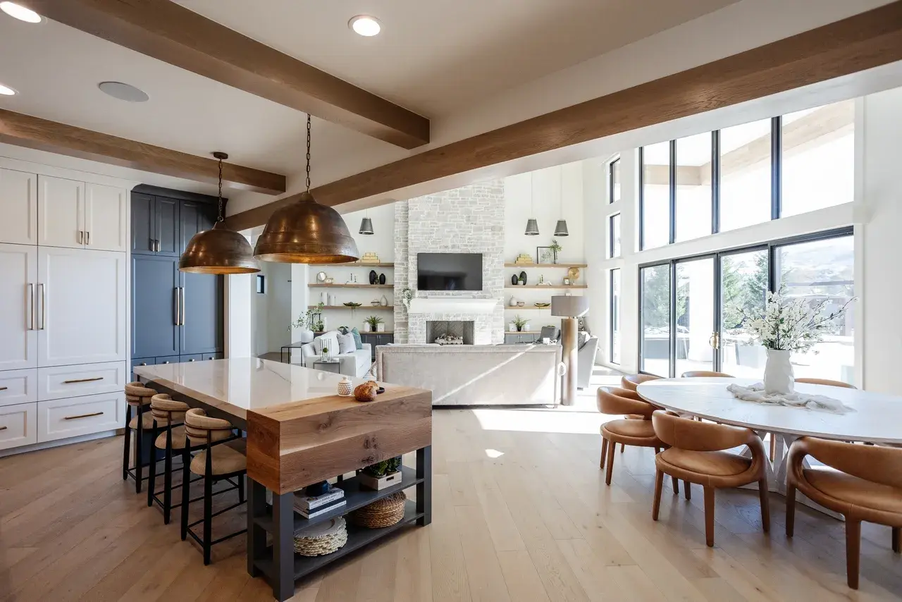 Open-concept kitchen and dining space with brass pendant lights, a large island, and floor-to-ceiling windows in a luxury custom home in Draper, Utah by E Builders