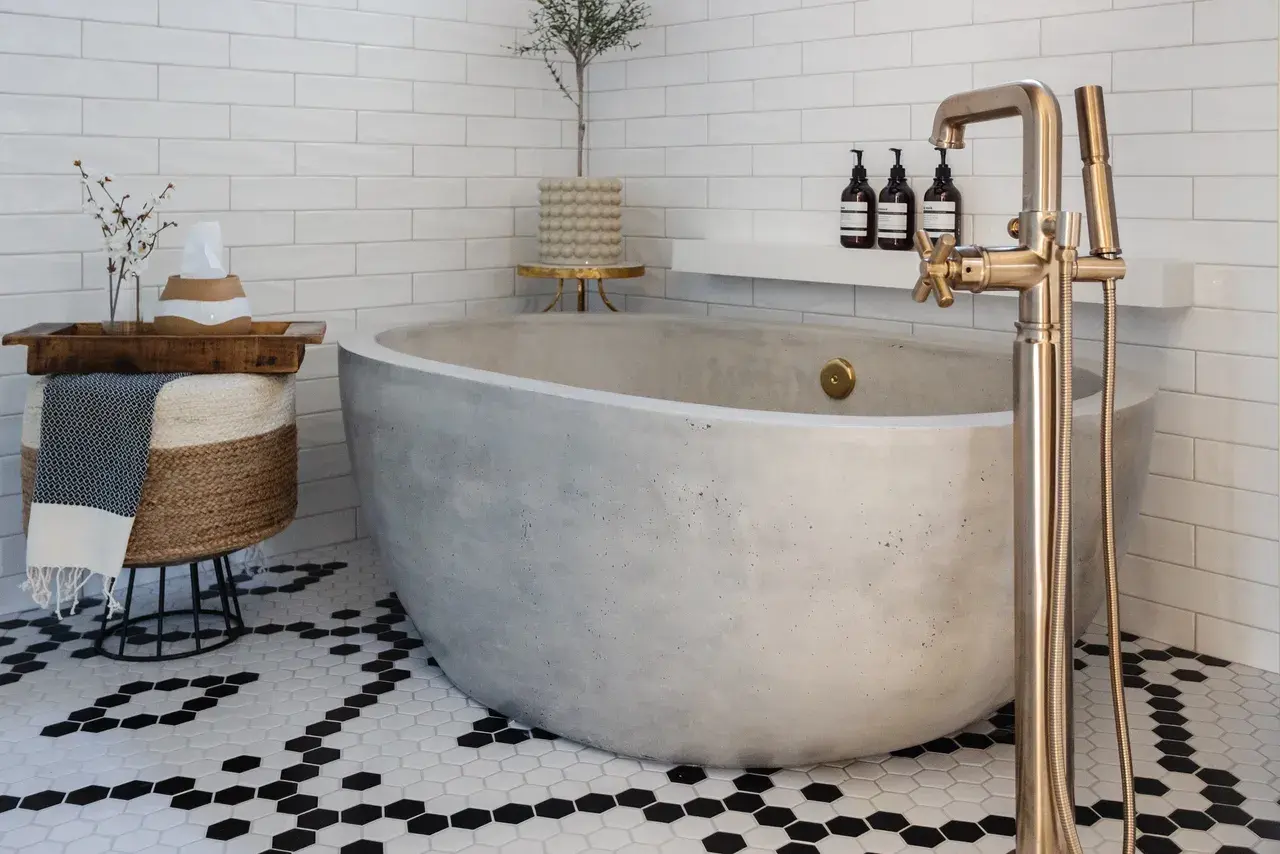 Serene and stylish bathroom with a concrete bathtub, geometric tile flooring, and natural decor in a luxury custom home in Draper, Utah by E Builders