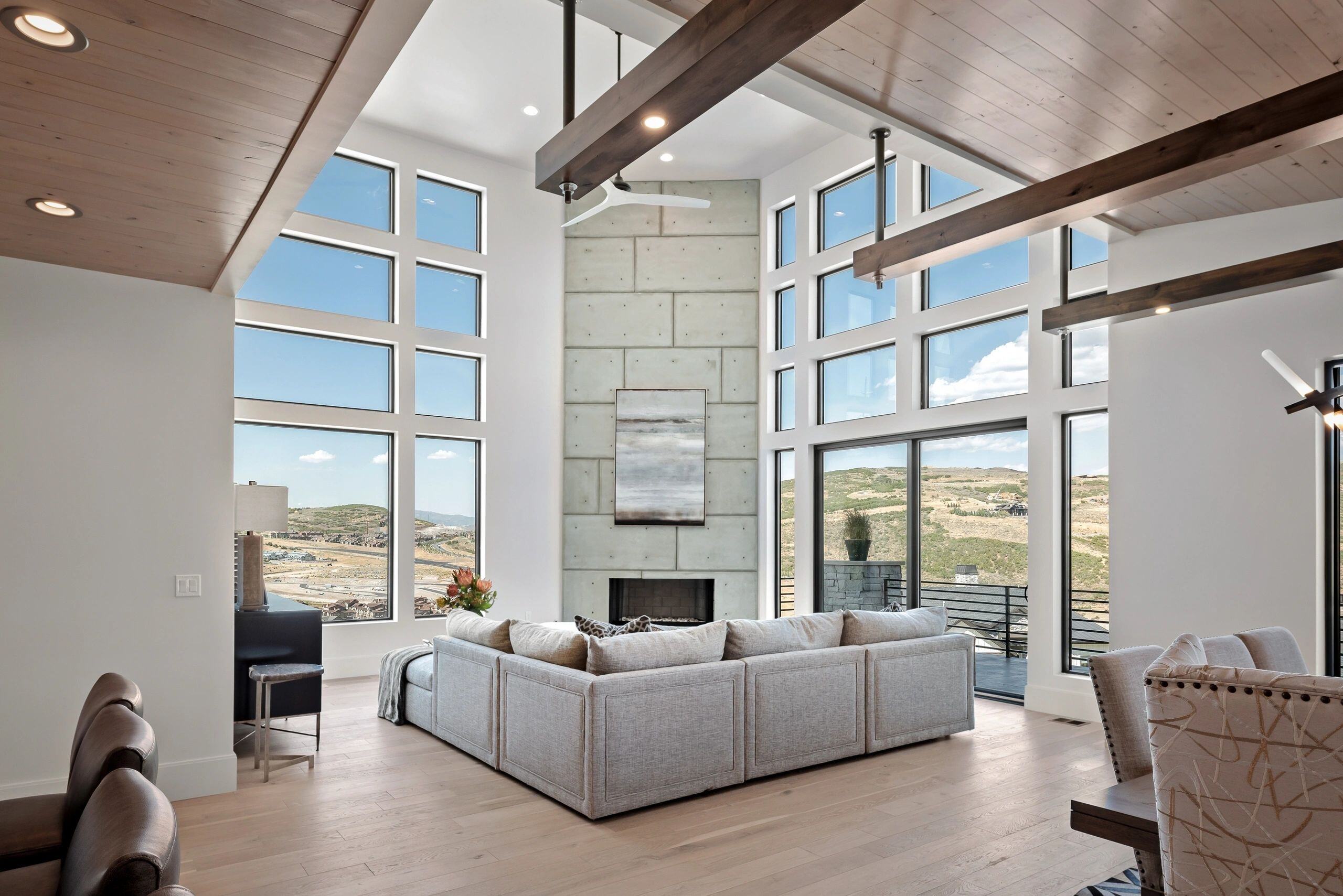 Floor-to-ceiling windows framing hillside views in a luxury living room in a custom home in Park City, Utah by E Builders