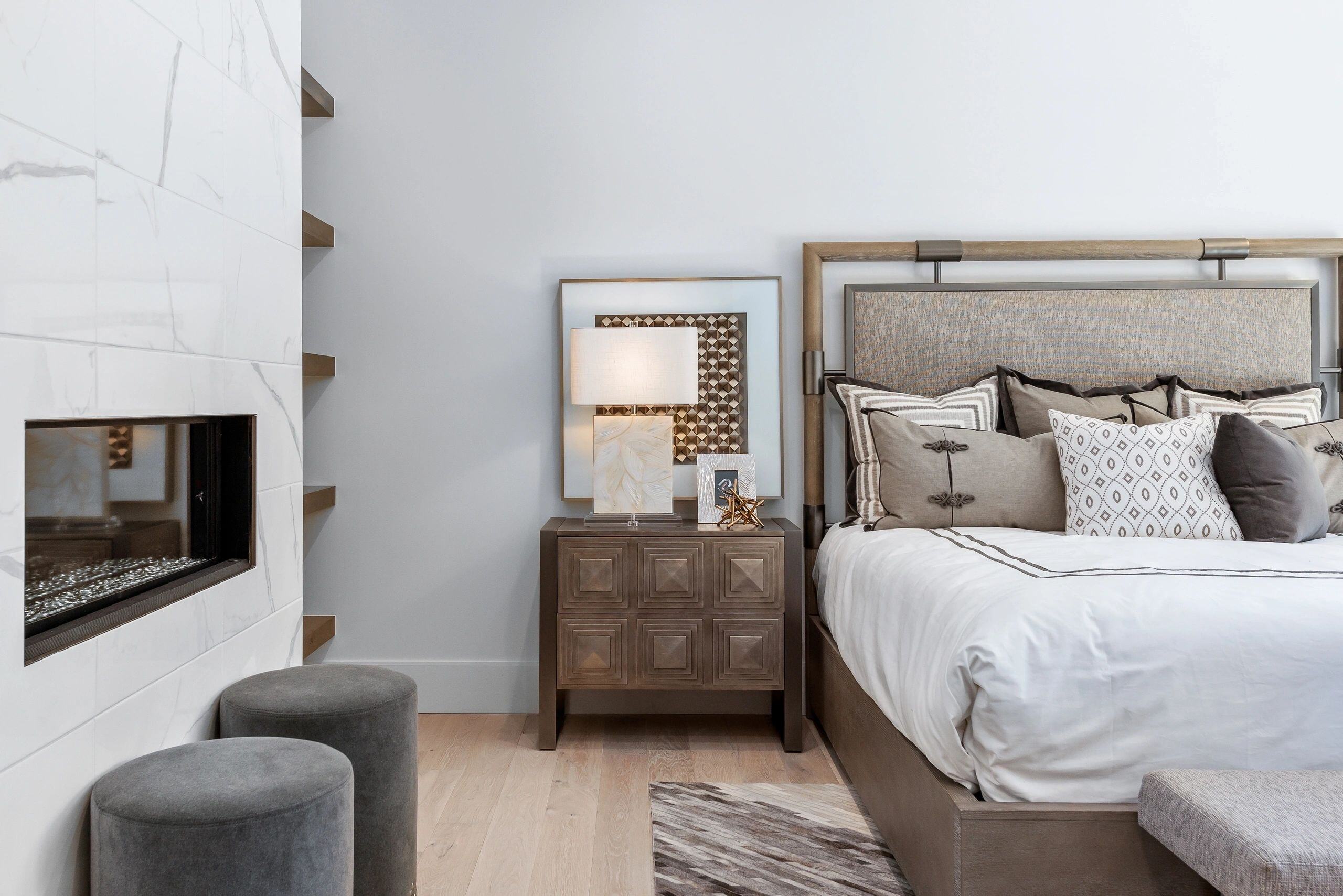 Nightstand with decorative lamp and framed art next to a plush bed in a custom home in Park City, Utah by E Builders