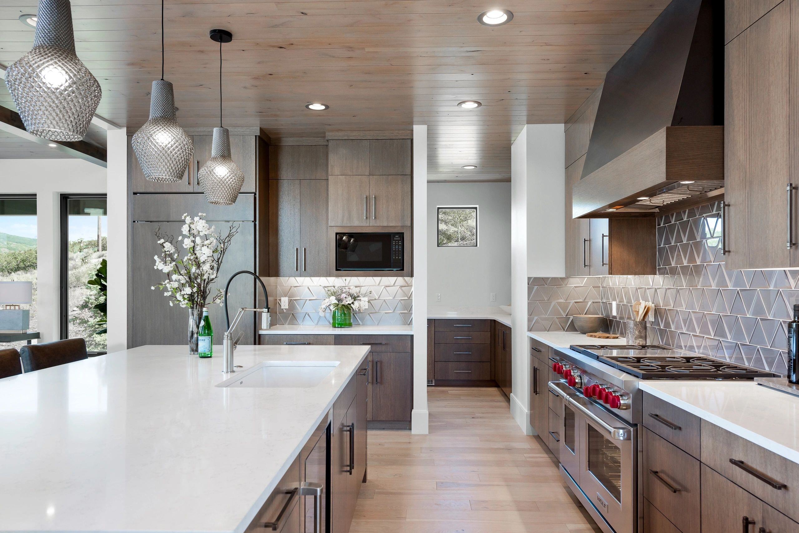 Open-concept kitchen with pendant lighting and wood cabinetry in a custom home in Park City, Utah by E Builders