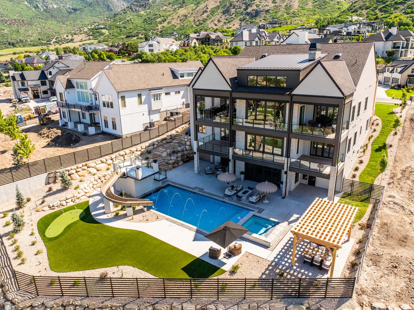 Aerial view of custom homes backyard with pool, pergola, and putting green in Room with a View featured in the 2025 Utah Valley Parade of Homes by E Builders