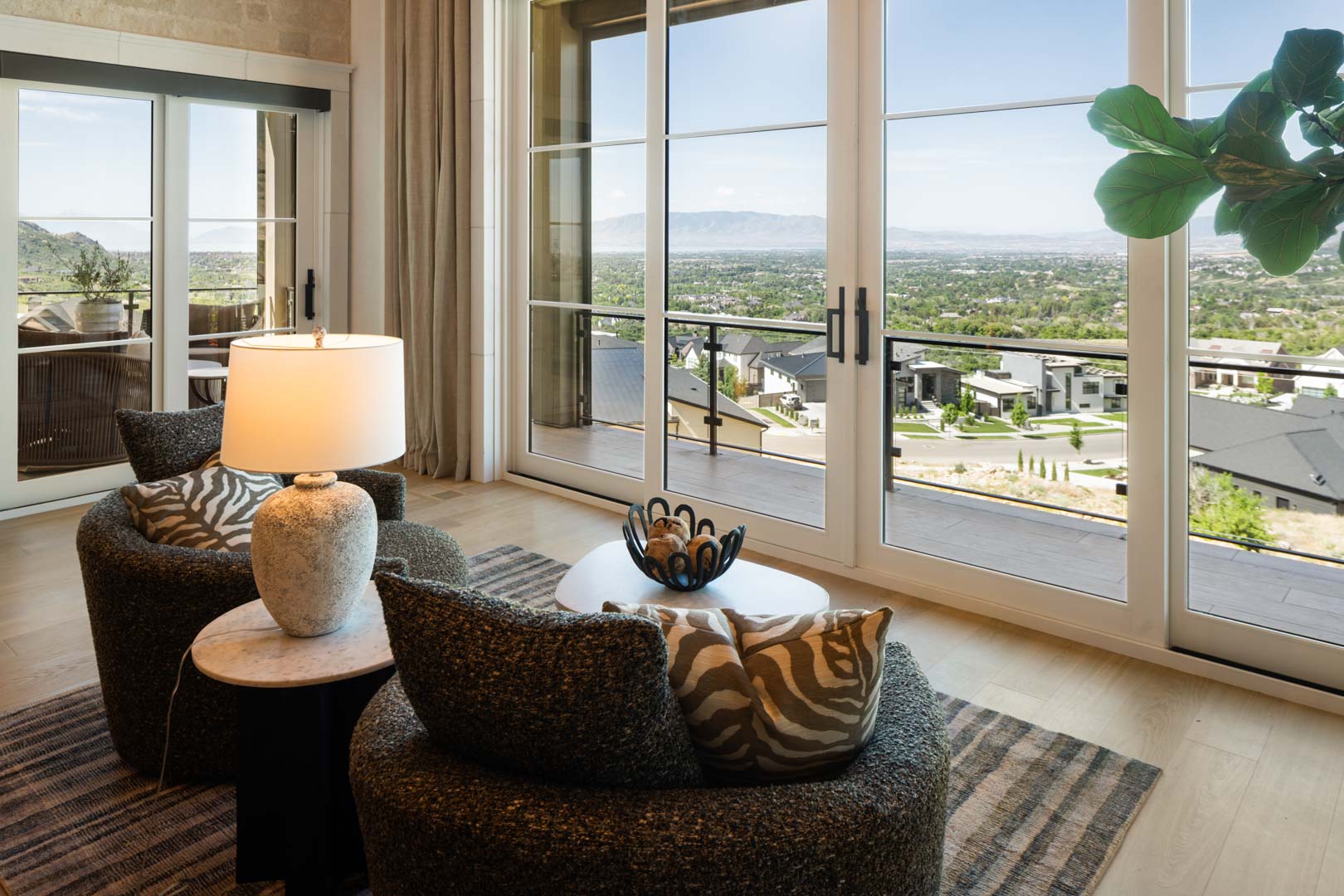 Cozy lounge chairs facing scenic valley views through large windows in custom home Room with a View featured in the 2025 Utah Valley Parade of Homes by E Builders