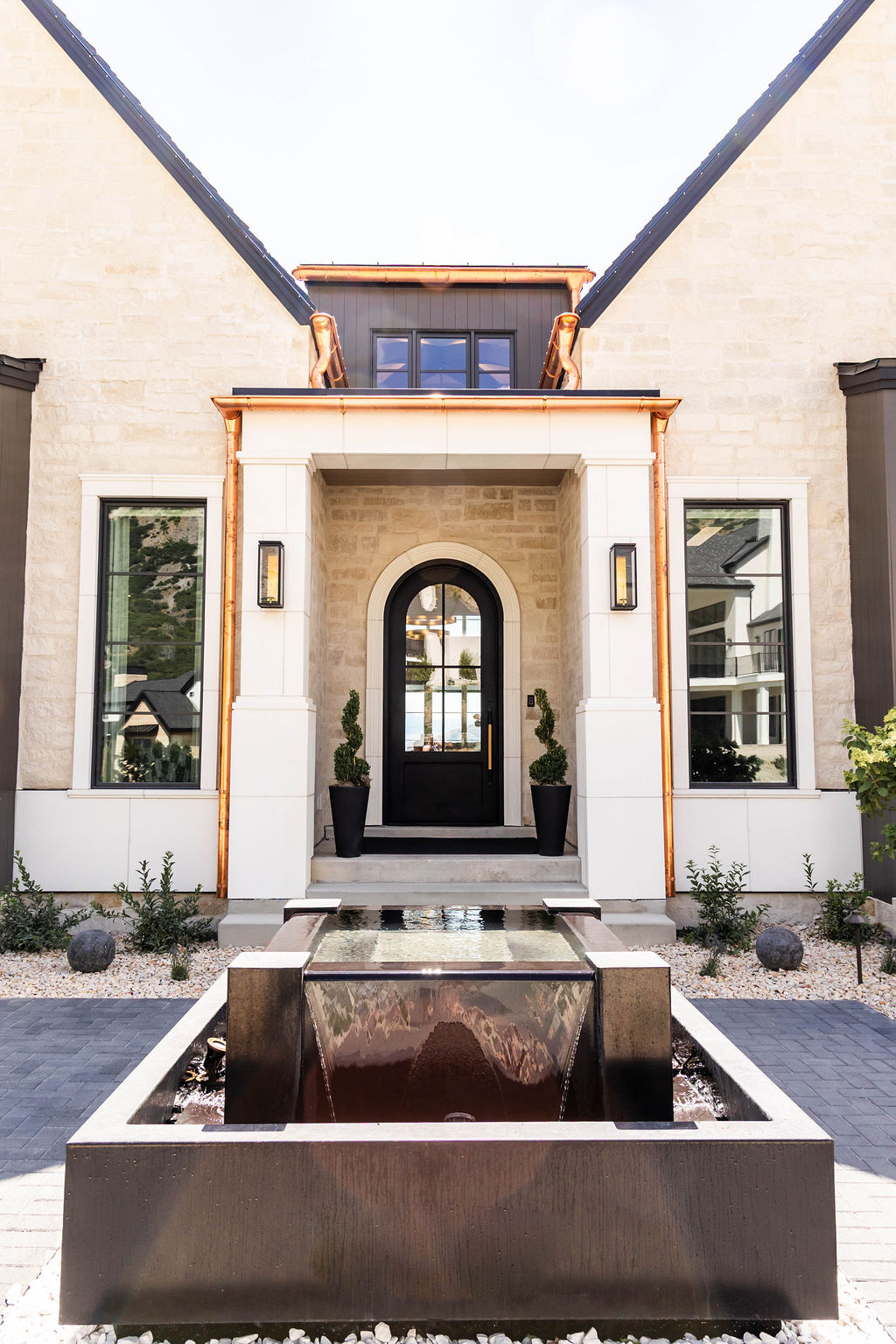Exterior grand front enterance with statement fountain and custom copper accents in the Room with a View custom home featured of the 2025 Utah Valley Parade of Homes by E Builders.
