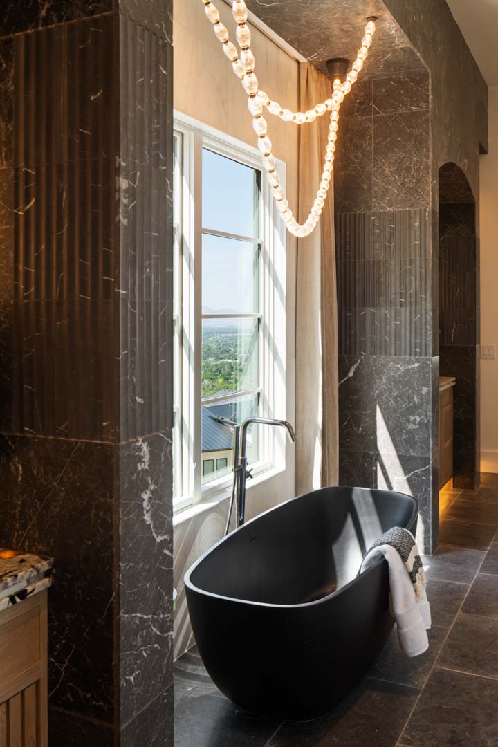 Freestanding matte black tub beneath window in luxury bathroom of custom home Room with a View featured in the 2025 Utah Valley Parade of Homes by E Builders