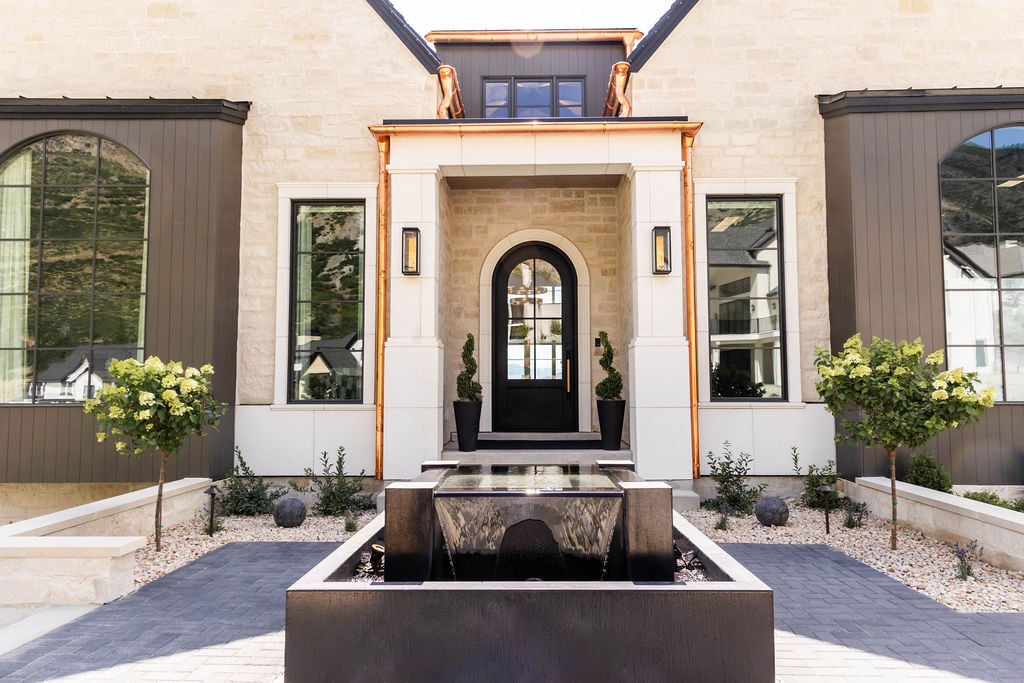 Front walkway leading to arched entry with black front door and modern landscaping of the Room with a View custom home featured in the 2025 Utah Valley Parade of Homes by E Builders