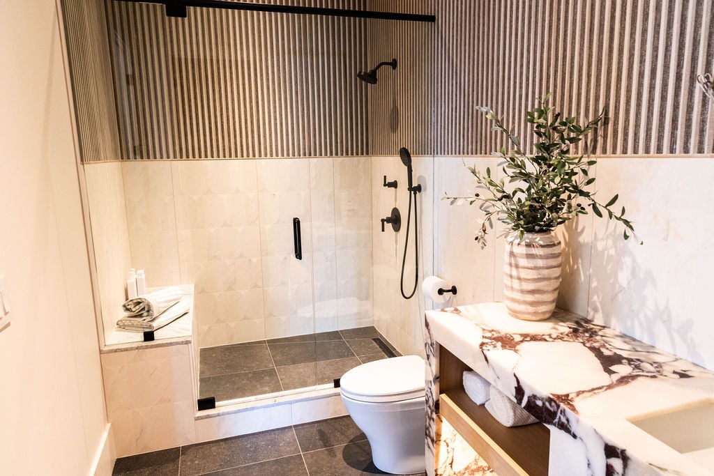 Modern guest bathroom with Calacata Viola Turko stone and vertical tile walls in the Room with a View custom home featured in the 2025 Utah Valley Parade of Homes by E Builders