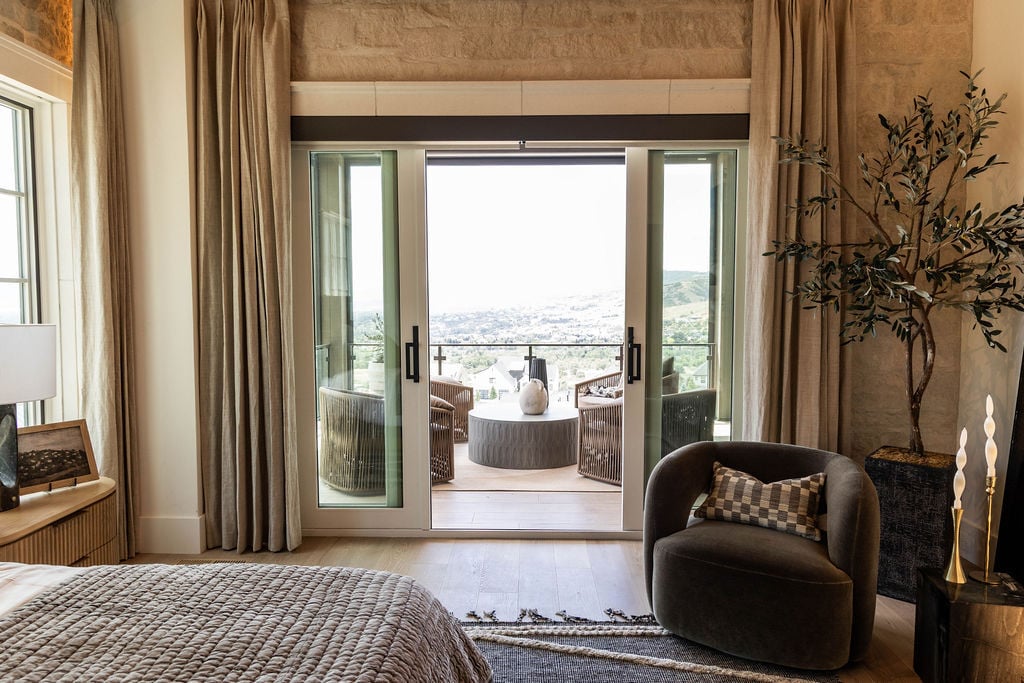 Primary bedroom seating area with white oak floors and balcony access in the Room with a View custom home featured in the 2025 Utah Valley Parade of Homes by E Builders
