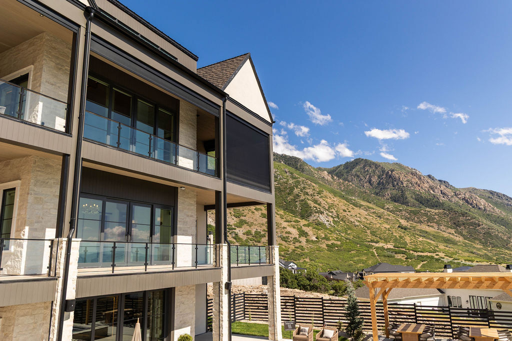 Rear elevation showcasing multiple balconies and stone exterior in the Room with a View custom home featured in the 2025 Utah Valley Parade of Homes by E Builders