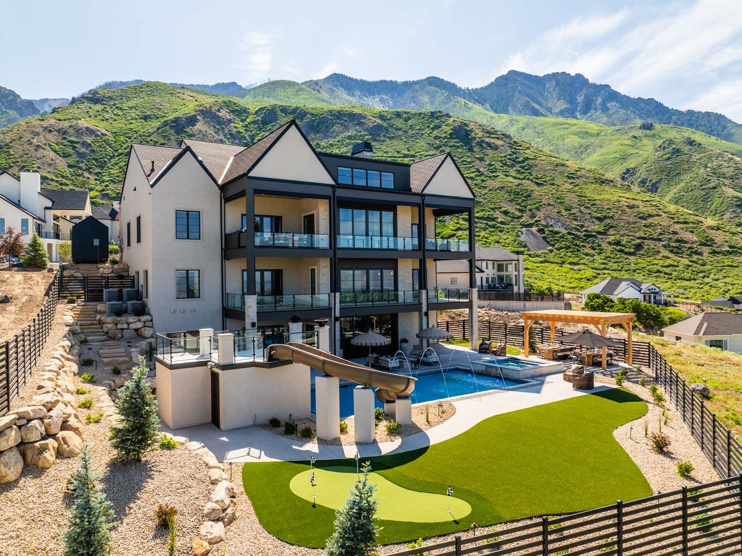 Rear exterior of three-story luxury home with pool and putting green in custom home Room with a View featured in the 2025 Utah Valley Parade of Homes by E Builders