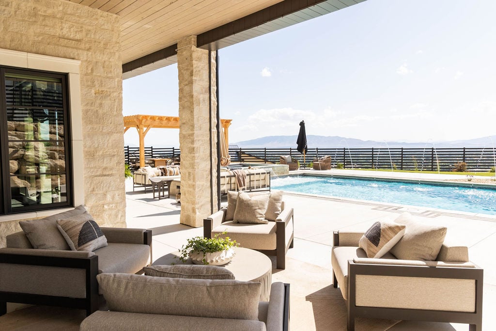 Shaded outdoor lounge area overlooking the pool in the Room with a View custom home featured in the 2025 Utah Valley Parade of Homes by E Builders